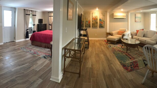 A spacious living area with a sofa, coffee table, and a dining table. There is a kitchen area with a microwave and stove.