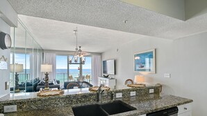A modern kitchen with granite countertops, a black sink, and a dishwasher.