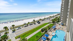 A resort with a pool, beach view, and a road with cars.