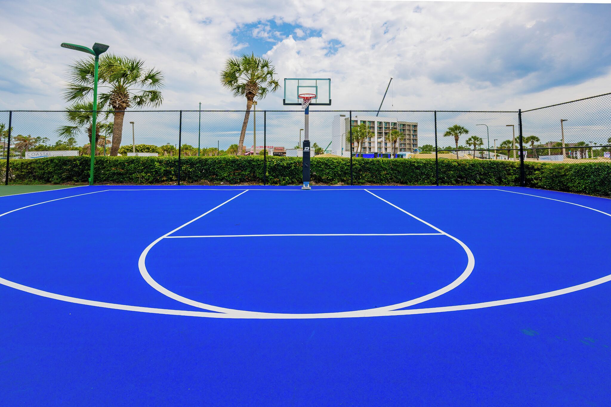 Get in a pickup game or just shoot some hoops on the vibrant blue basketball court at Phoenix III surrounded by palm trees