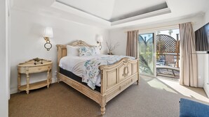 Un dormitorio con una cama grande, una mesita de noche, una lámpara y vistas al exterior.