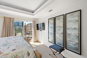 Une chambre d’hôtel avec un lit, une chaise et trois grandes peintures abstraites accrochées au mur.