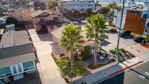 Zona residencial con vista al mar, con casas, palmeras y un estacionamiento.