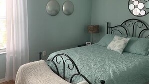 Un dormitorio con cama, ventilador de techo y ventana con cortinas.