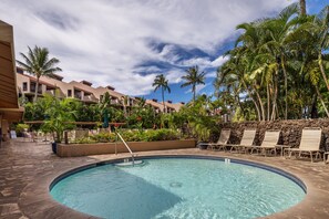 A pool area with lounge chairs and palm trees.