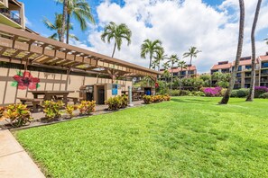 A hotel courtyard with a covered patio, palm trees, and a grassy lawn.