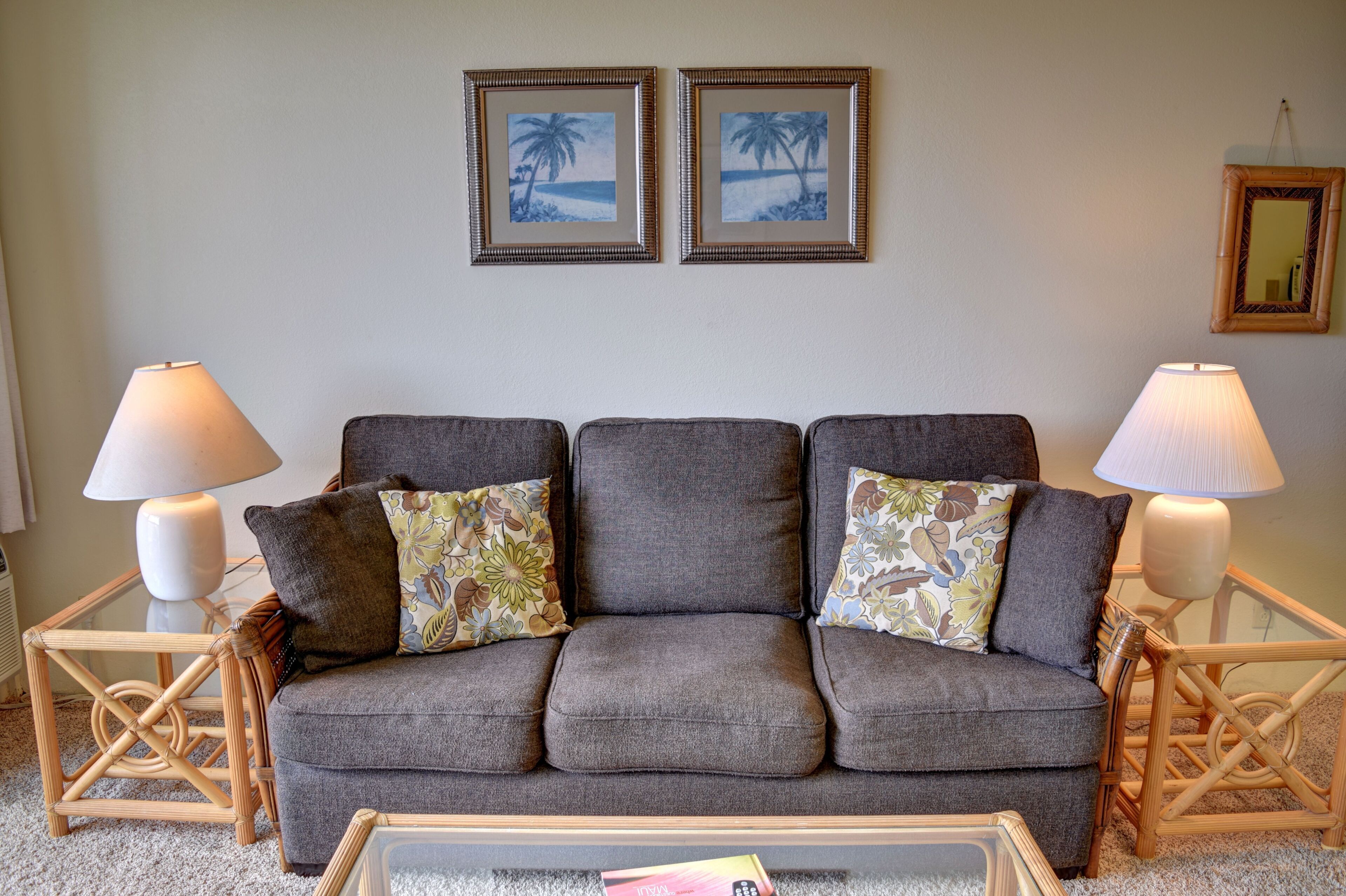 A living room with a grey sofa, two side tables with lamps, and two framed pictures on the wall.
