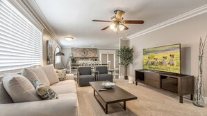 Ein Wohnzimmer mit Sofa, Couchtisch, Fernseher und Deckenventilator.