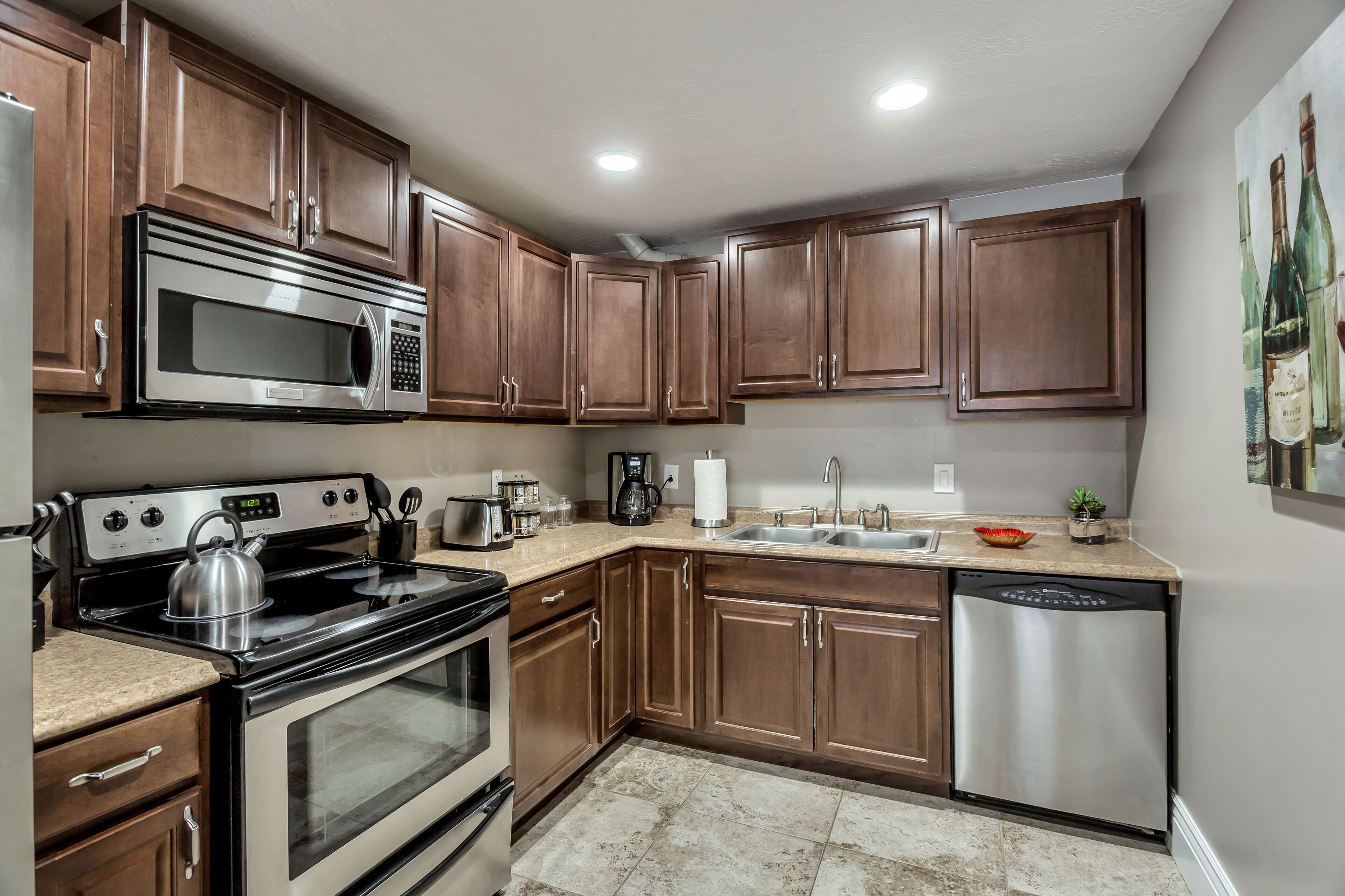 A kitchen with wooden cabinets, stainless steel appliances, a granite countertop, and a tiled backsplash.
