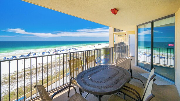 A balcony with a view of the beach, a table, chairs, and a railing. - Three Bedroom at Phoenix 5 with Reserved Parking (Orange Beach)