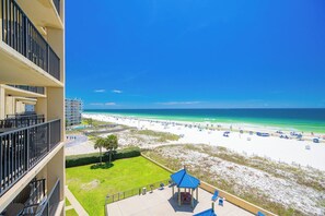 Ein Strandhotel mit Balkonen, einem Strand und einem strahlend blauen Himmel.