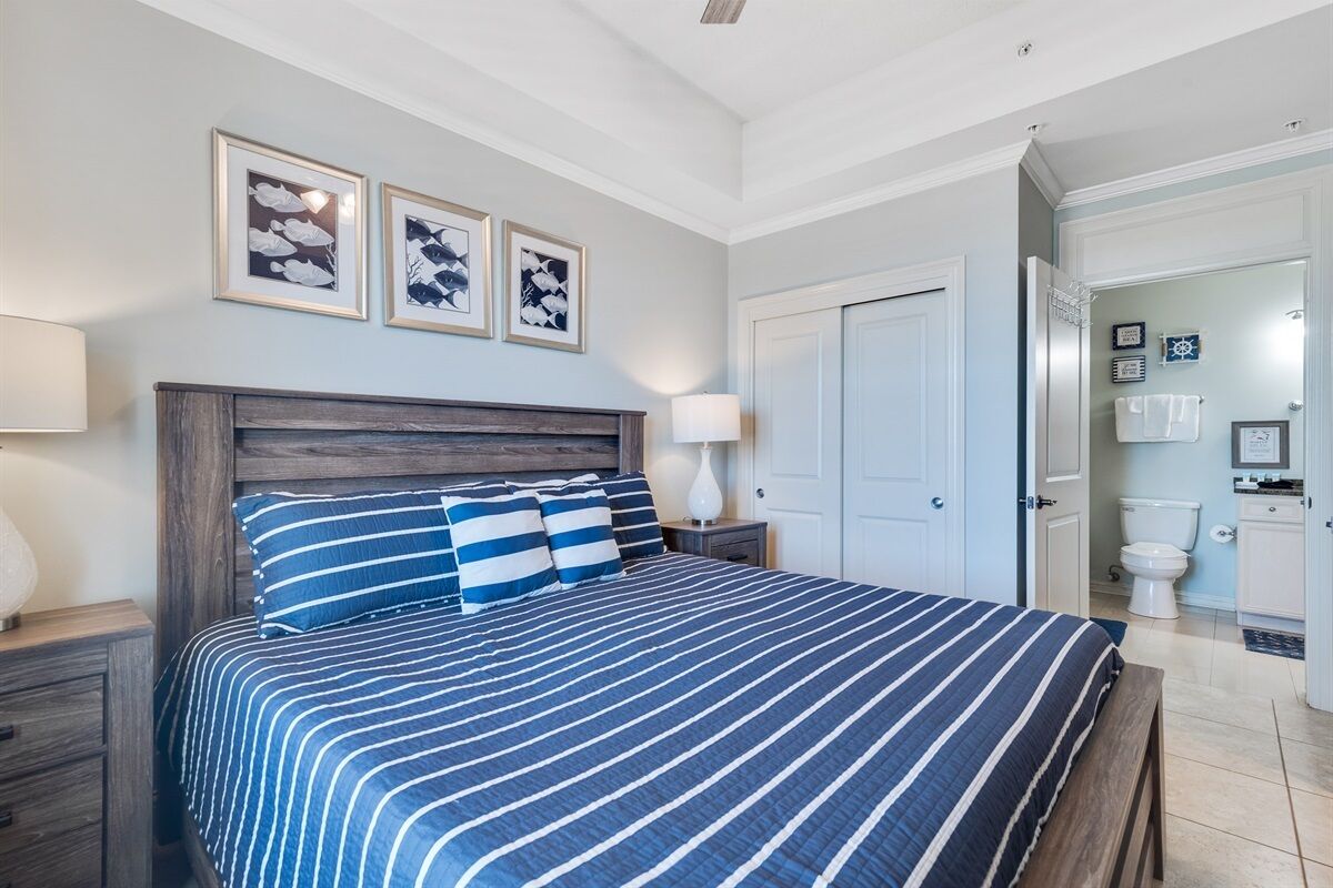 A bedroom with a large bed, a wooden headboard, and three framed pictures on the wall.