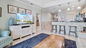A modern kitchen with a central island, bar stools, and a dining area with a wooden table. - Waterfront 1BR + Bunk Alcove at The Wharf • Sleeps • Amazing Views • Oasis Pool (Orange Beach)