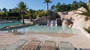 A pool area with lounge chairs and a rock formation. - Waterfront 1BR + Bunk Alcove at The Wharf • Sleeps • Amazing Views • Oasis Pool (Orange Beach)