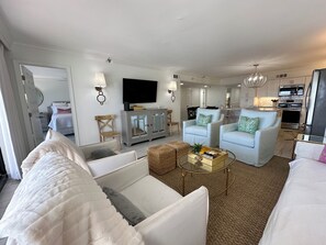 Una sala de estar moderna con un sofá, sillones, una mesa de centro y un televisor.