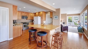 A modern kitchen with wooden cabinets, stainless steel appliances, and a central island with stools. - 11LT Lower: 2BD Home with Stunning Panoramic Views,BBQ, Spacious Balcony, WIFI (Avalon)