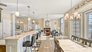 Une cuisine spacieuse dotée d’un grand îlot central, de tabourets de bar et d’un coin repas avec une grande table et des chaises.