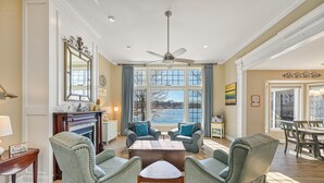 Un salon spacieux doté d’une cheminée, de deux fauteuils, d’une table basse et d’un coin repas avec une table et des chaises.