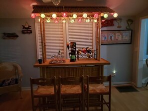 A bar area with a counter, chairs, and a window with blinds.