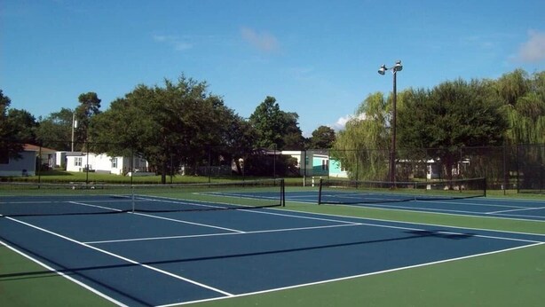 En tennisplan med nät, omgiven av träd och byggnader.