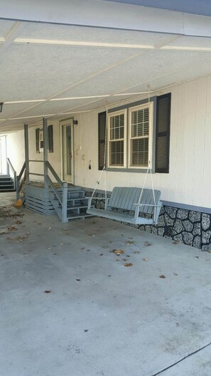 A porch with a swing set, a staircase, and a stone wall.