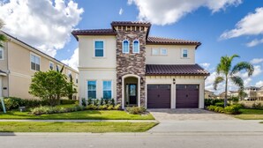 A two-story residential building with a central tower, a garage, and a well-maintained lawn.