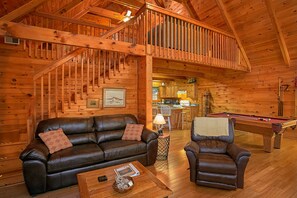 L’intérieur d’un chalet en bois chaleureux et accueillant, avec un canapé en cuir, une table de billard et un coin repas.