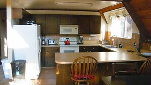 A compact kitchen with a refrigerator, microwave, stove, and sink.