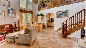 A spacious living area with a high ceiling, a dining table, a sofa, and a staircase leading to an upper level. - 5 STAR ⭐️⭐️⭐️⭐️⭐️ STUNNING PRIVATE LV ESTATE! (Las Vegas)