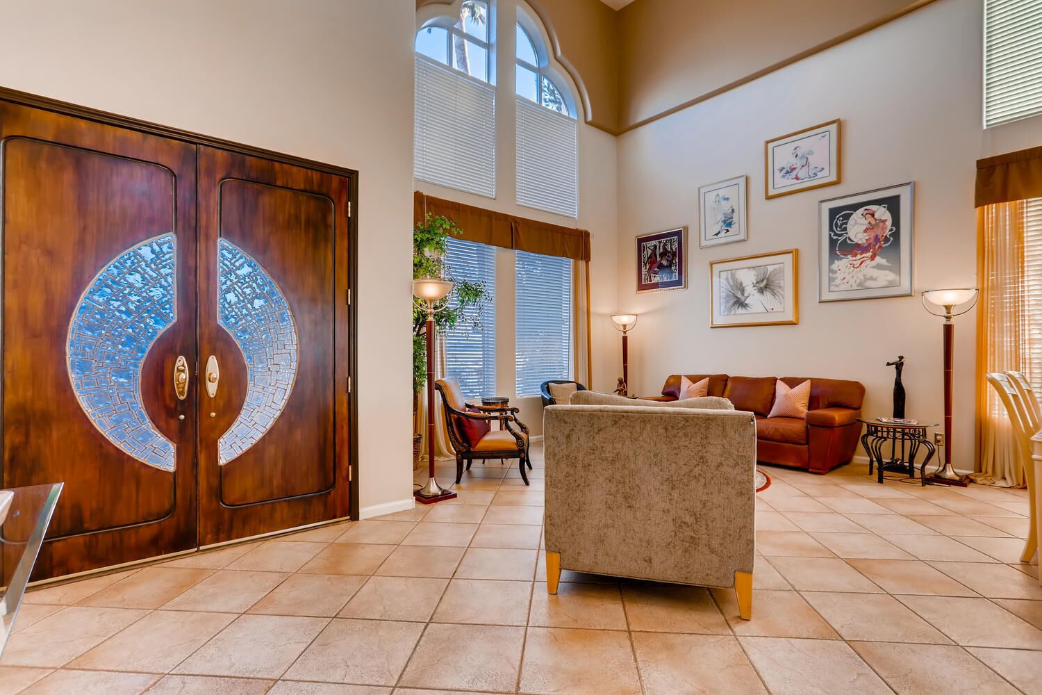 A spacious living room with a large wooden door, a sofa, a coffee table, and a dining area with a table and chairs.