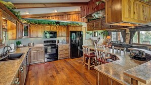 Una cocina amplia con armarios de madera, encimera de granito y comedor con muebles rústicos.