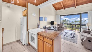 Una cocina moderna con techo de madera, una isla grande y un comedor con vistas al exterior.