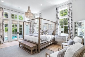 A spacious bedroom with a four-poster bed, a wooden bench, a nightstand, and a chair. - Luxury 3-story WaterColor Home. Private Pool, Bikes, Golf Cart, Lots of Amenities. Ideal for Groups! (Santa Rosa Beach)