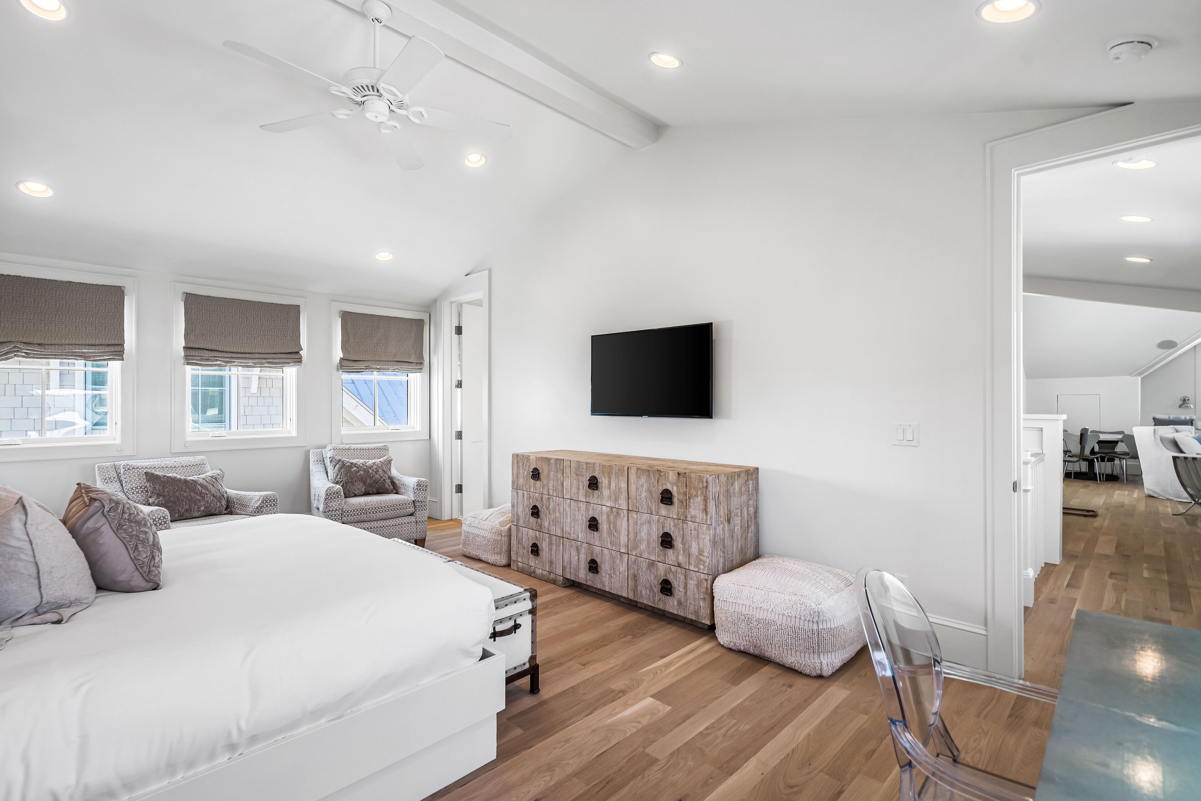 Une chambre dotée d’un grand lit, d’une commode en bois, d’un téléviseur à écran plat et d’un coin repas avec une table et des chaises.