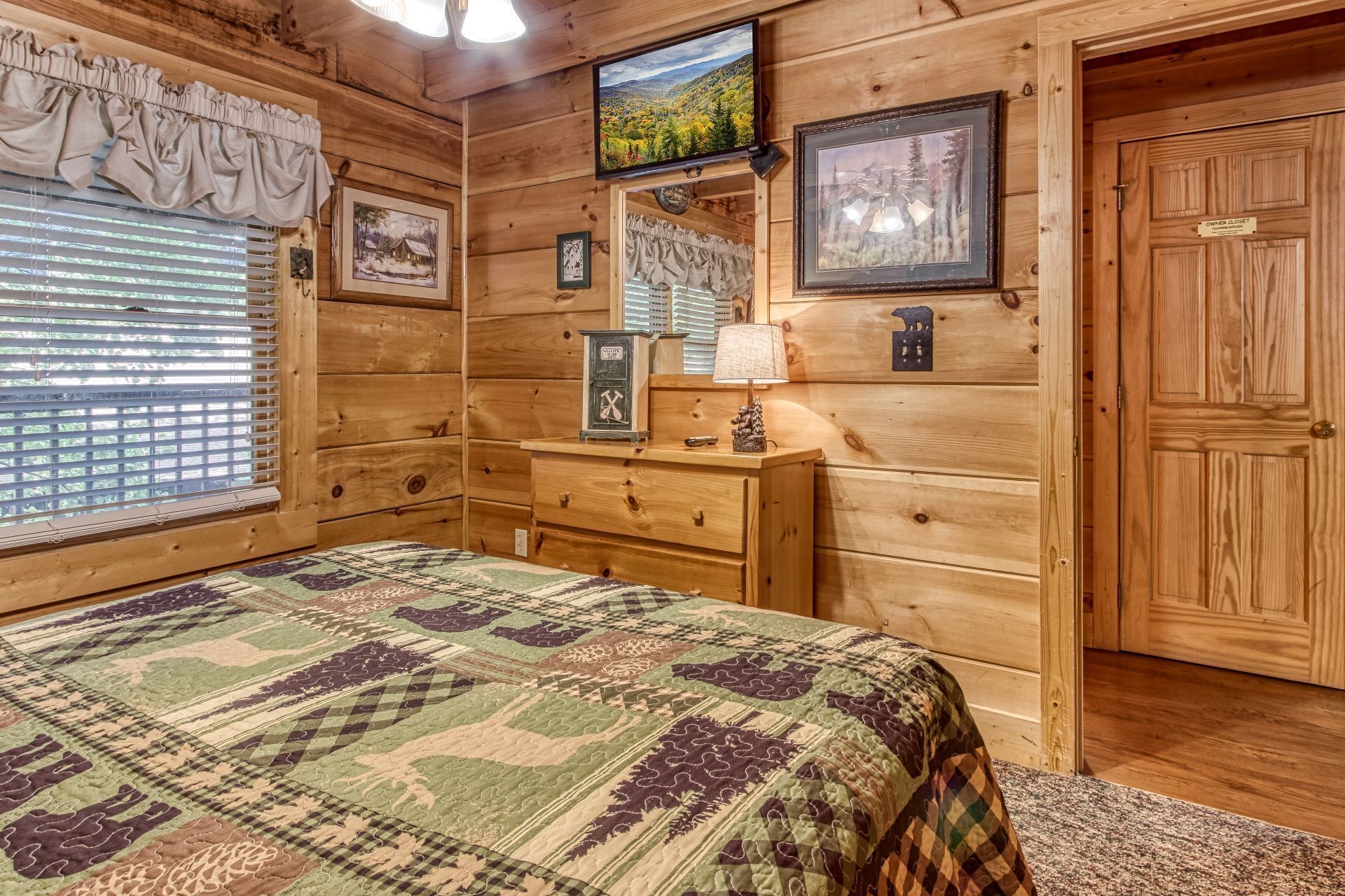 Une chambre dans une cabane en bois, avec un lit, une commode et une fenêtre équipée de stores.