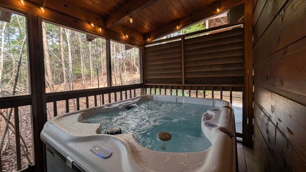 A hot tub with a wooden deck and a view of a forest. - ER245 – Almost Heaven  Great Location – Close to town! (Pigeon Forge)