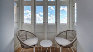 A room with a view through large windows, two wicker chairs, and a small round table. - 66 Saint Pauls & Spa (Valletta)