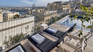 A rooftop terrace with two lounge chairs, a small pool, and a view of the cityscape. - 66 Saint Pauls & Spa (Valletta)