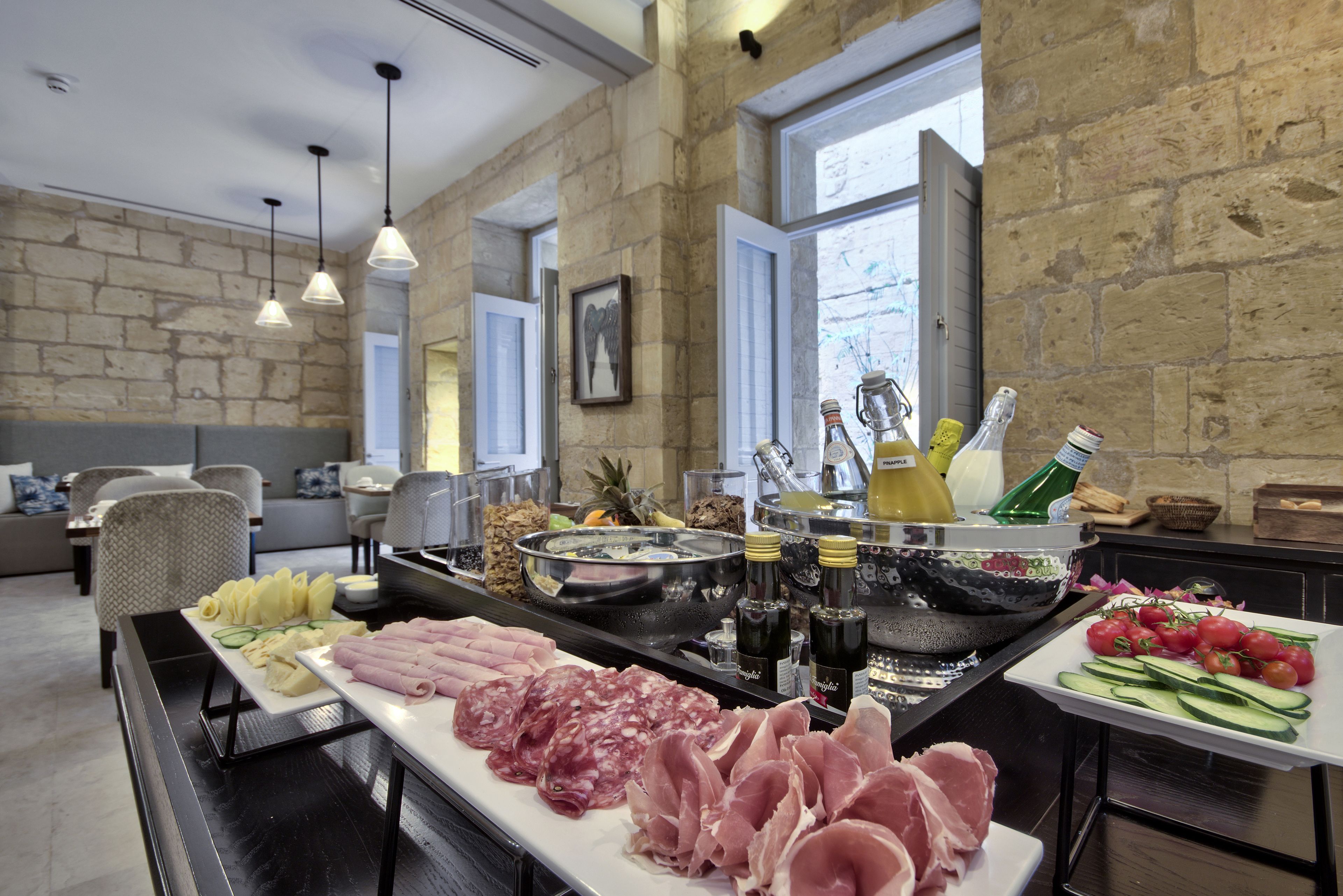 A buffet with various meats, cheeses, and vegetables, a hot tub, and a stone wall interior.