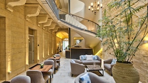 A spacious indoor area with a spiral staircase, seating arrangements, and a large potted plant. - 66 Saint Pauls & Spa (Valletta)