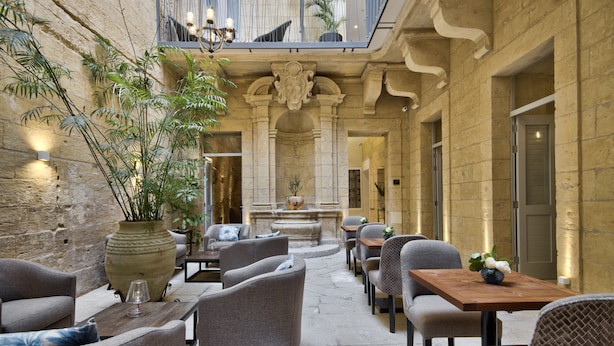 A spacious outdoor seating area with stone walls, modern furniture, and potted plants. - 66 Saint Pauls & Spa (Valletta)