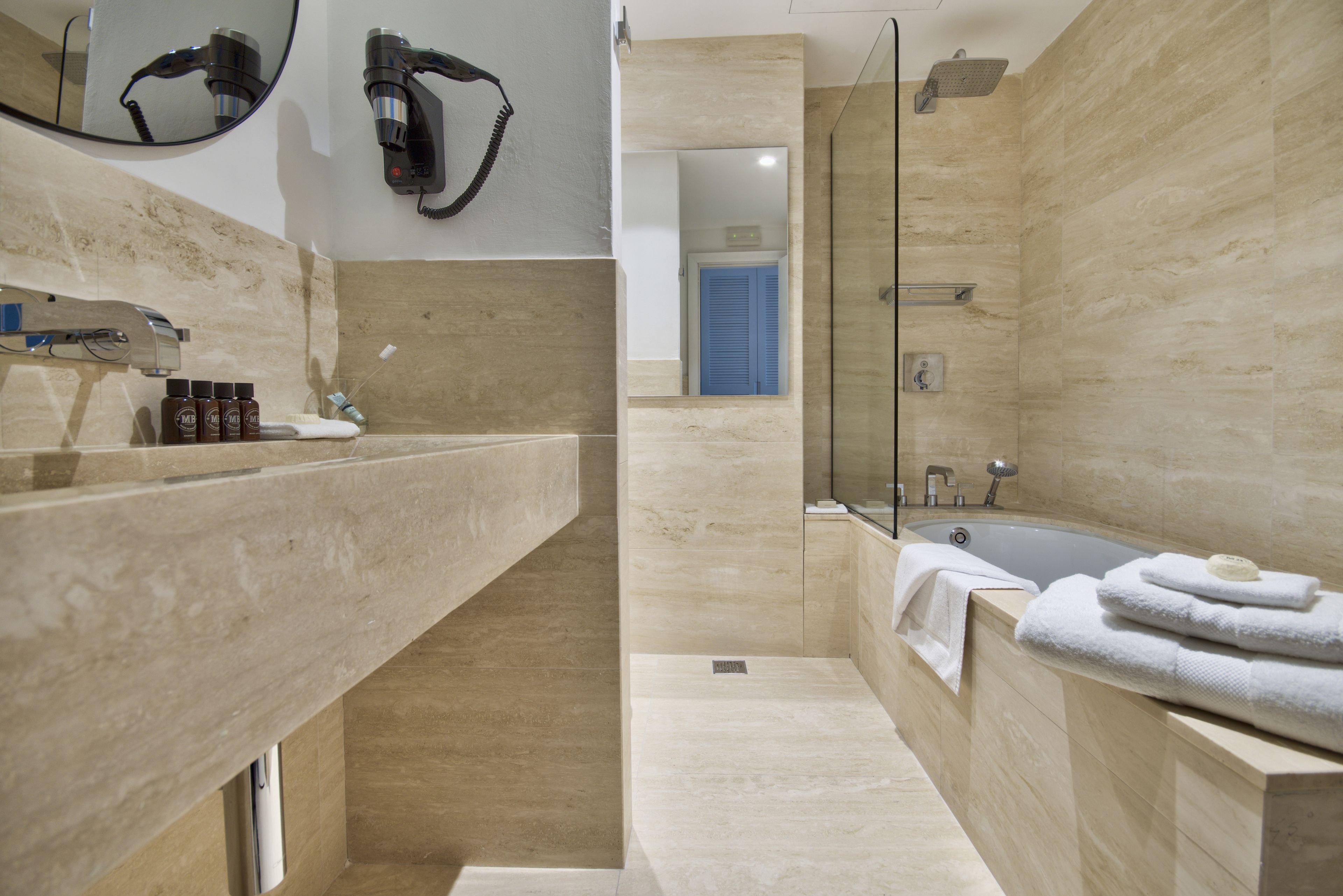 Ein modernes Badezimmer mit einer großen Badewanne, einer Duschkabine und einem Waschtisch mit Spiegel und Fön.