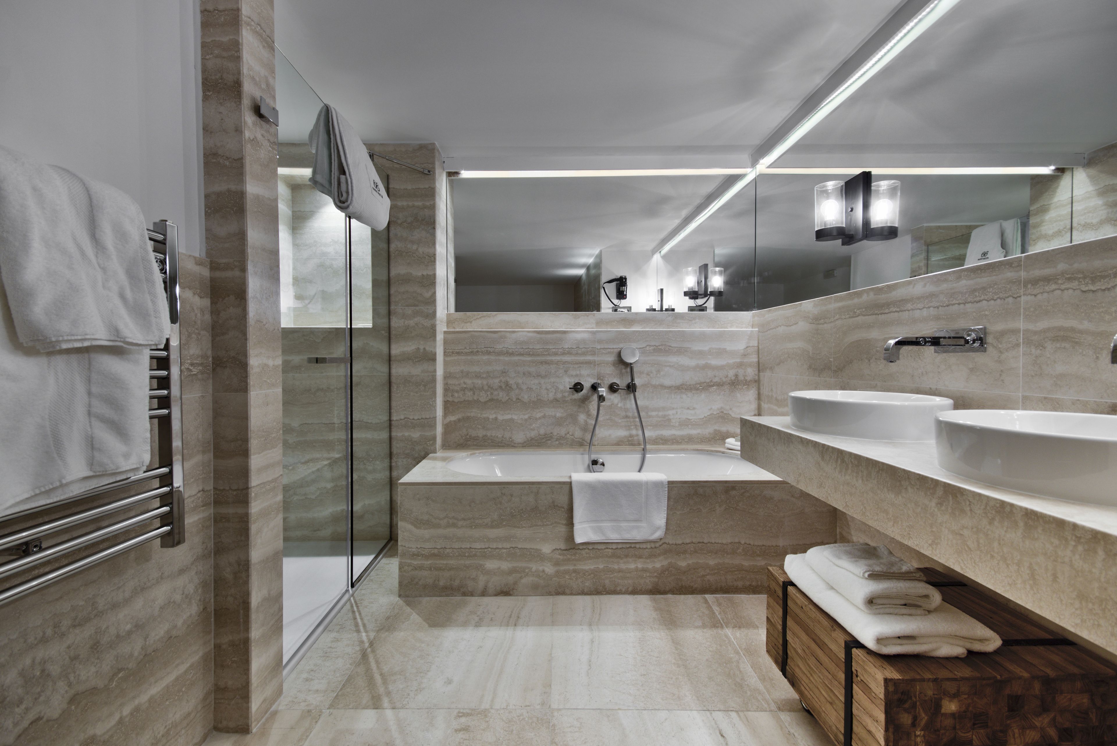 Un baño moderno con ducha de vidrio, una bañera independiente y dos lavamanos.