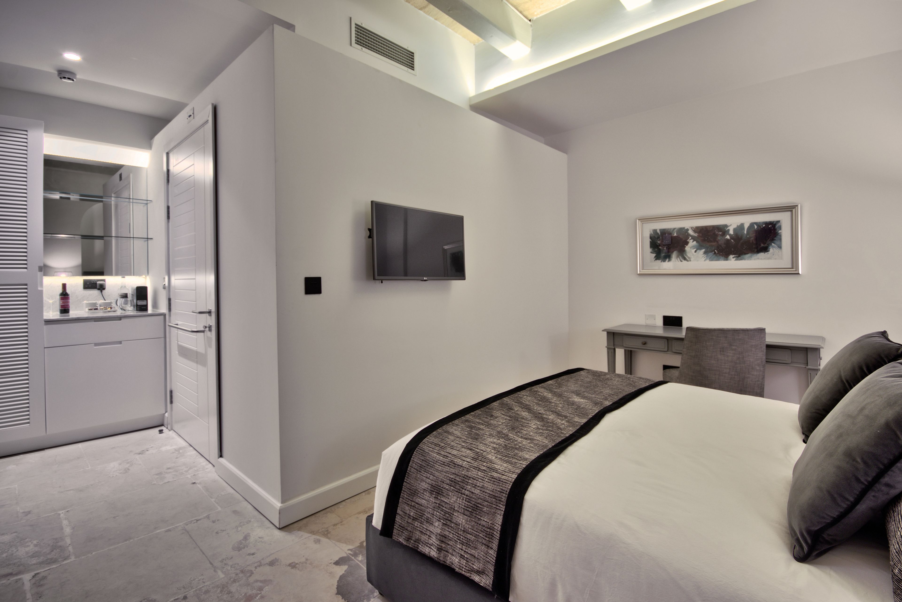 A modern bedroom with a bed, a desk, a television, and a wardrobe.