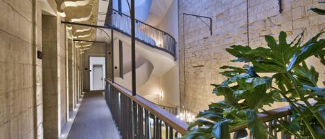 A modern interior with a spiral staircase, stone walls, and a plant in the foreground.