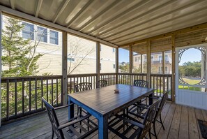A covered outdoor deck with a table and chairs, overlooking a residential area.