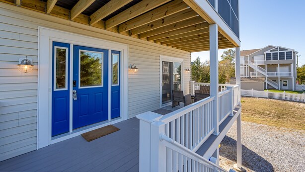 A two-story house with a covered porch, a blue front door, and a white railing. - Close to the Beach, Pet Friendly/Tesla Charger/2-3 Night Stays Off Season (Milton)