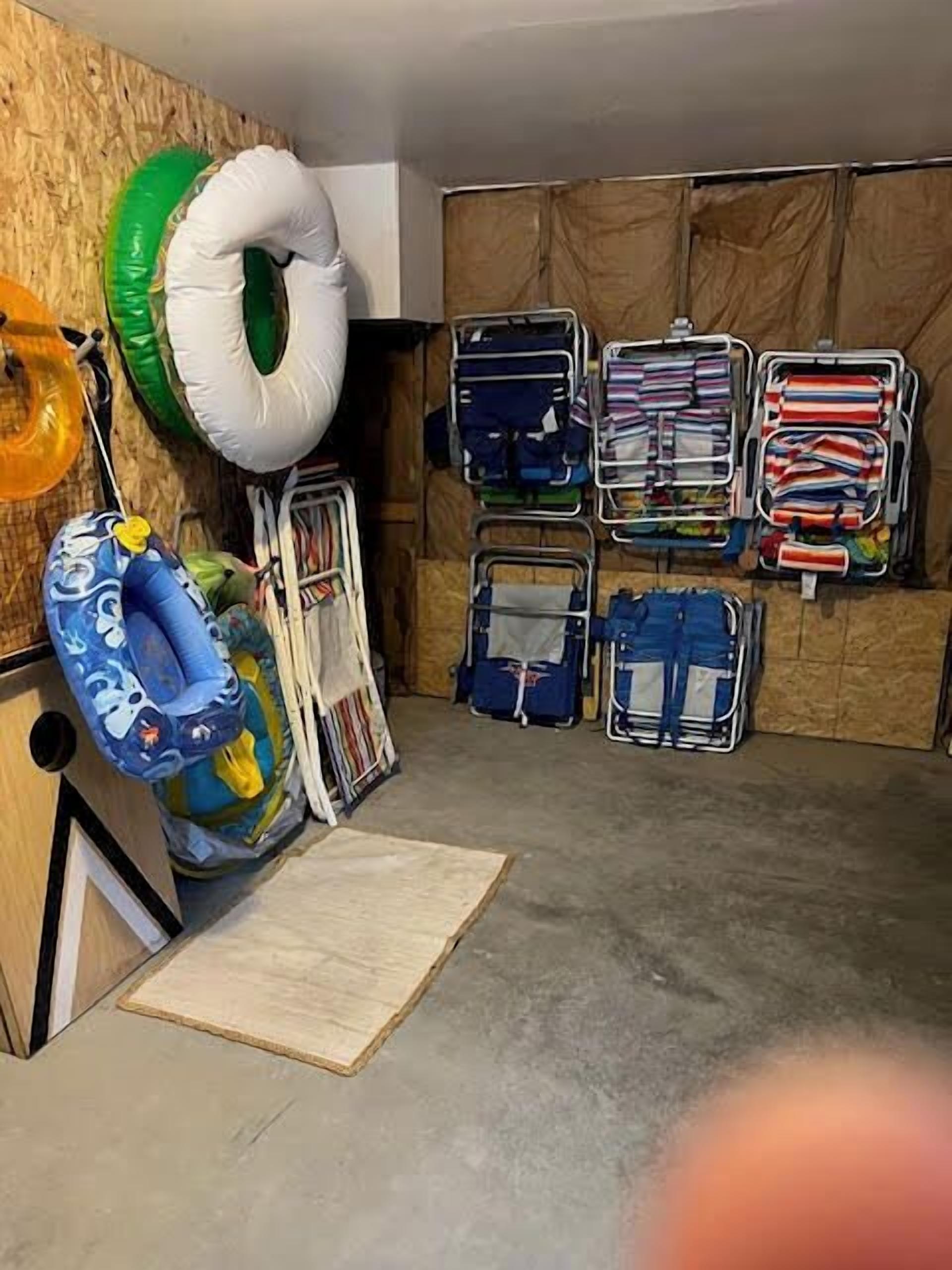 A room with a wooden wall, a green and white inflatable ring, a blue inflatable pool, and several neatly organized suitcases.