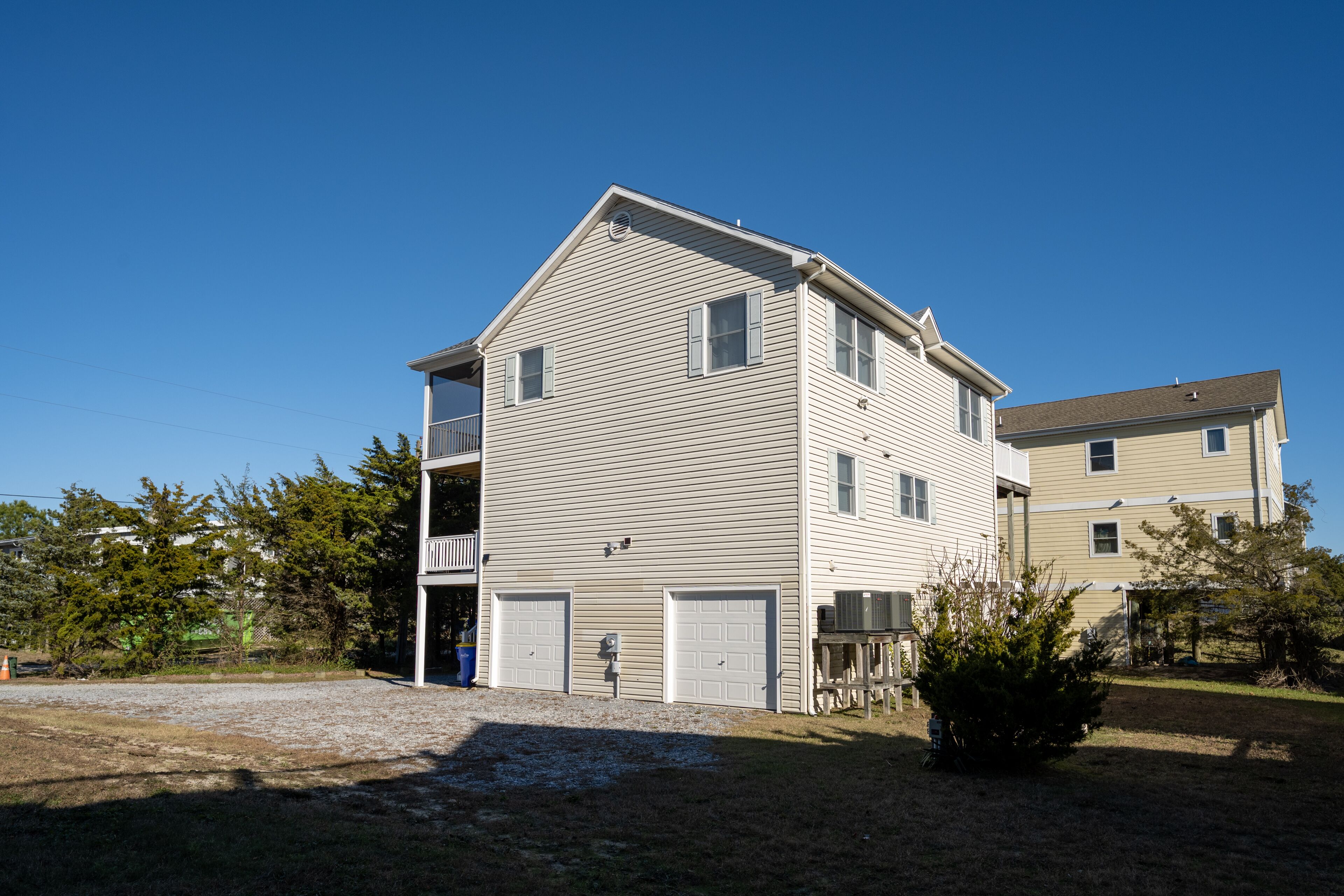 A two-story residential building with a front porch, two garages, and a small front yard.