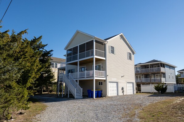 A two-story building with a balcony on the upper floor, a staircase leading to the balcony, and a garage door.